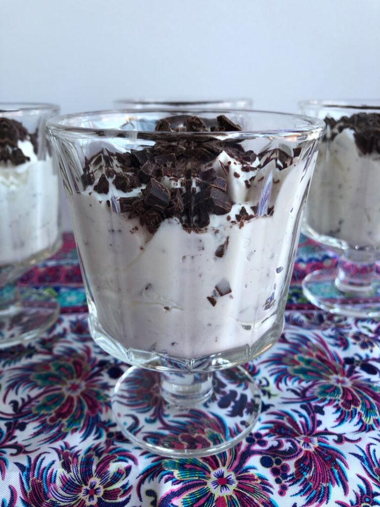 Stracciatella mousse topped with chopped chocolate in dessert dishes.