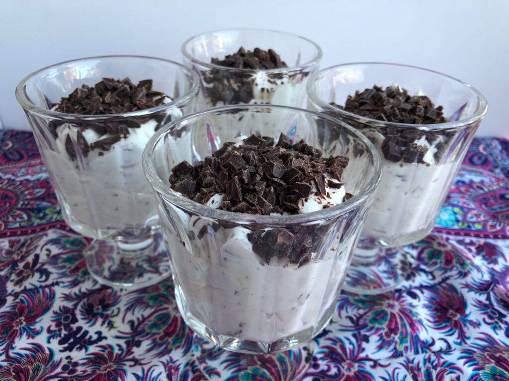Stracciatella mousse topped with chopped chocolate in dessert dishes.