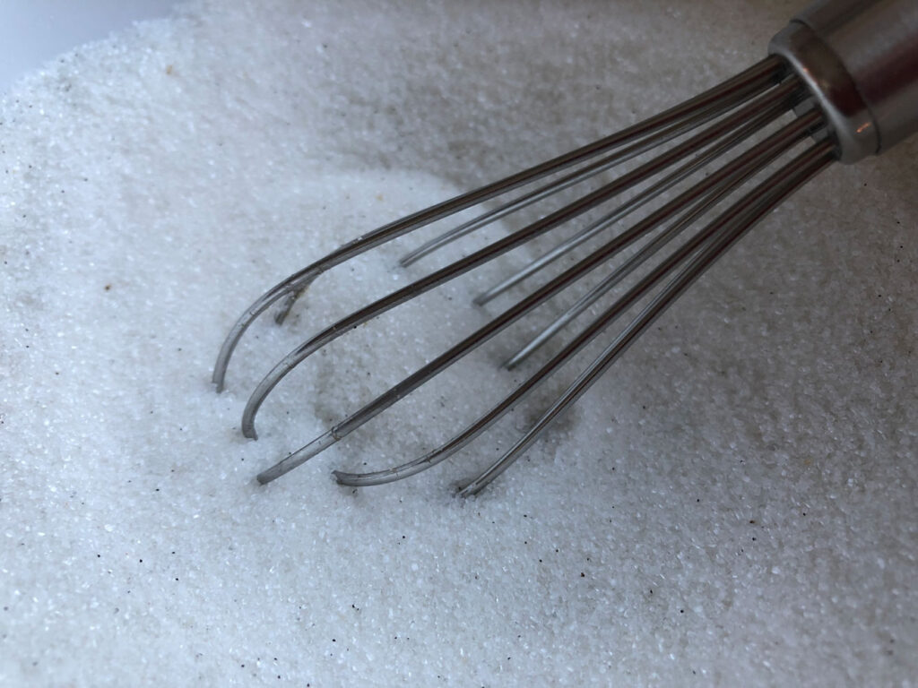 Sugar and vanilla bean seeds mixed with a whisk