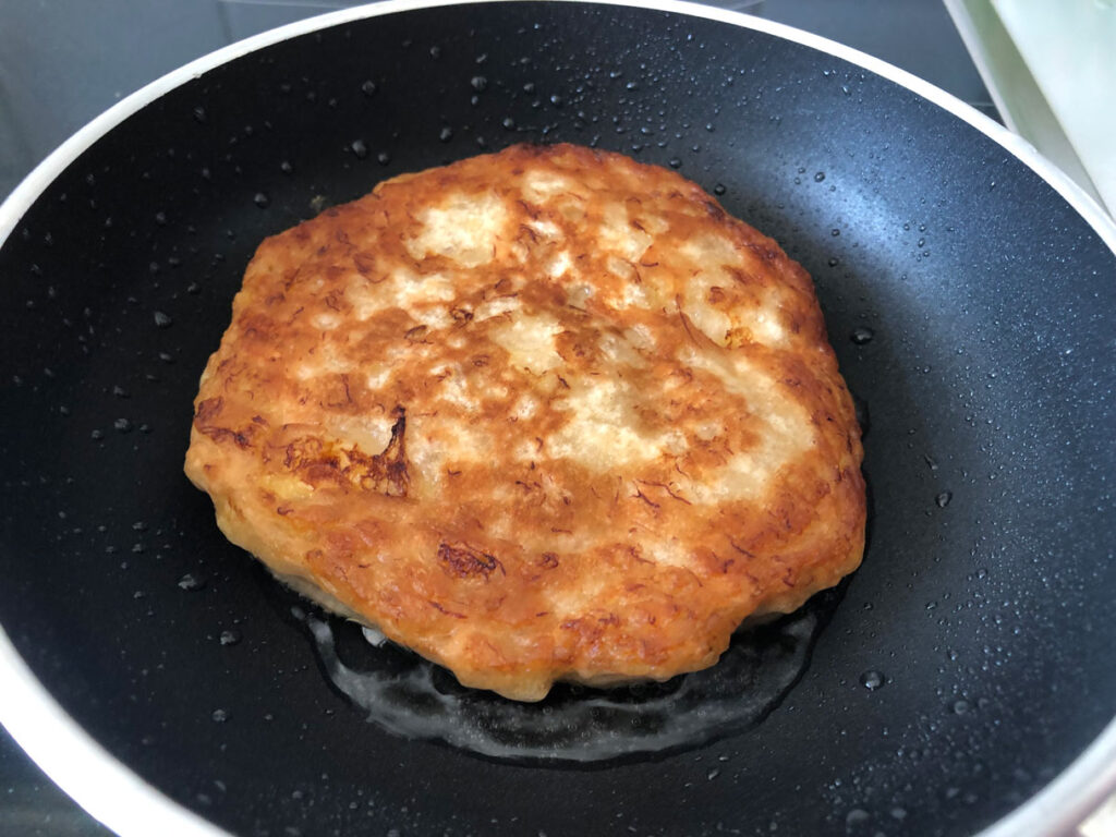 Jamaican banana fritters, of which one side is already deep-fried, in a pan with oil