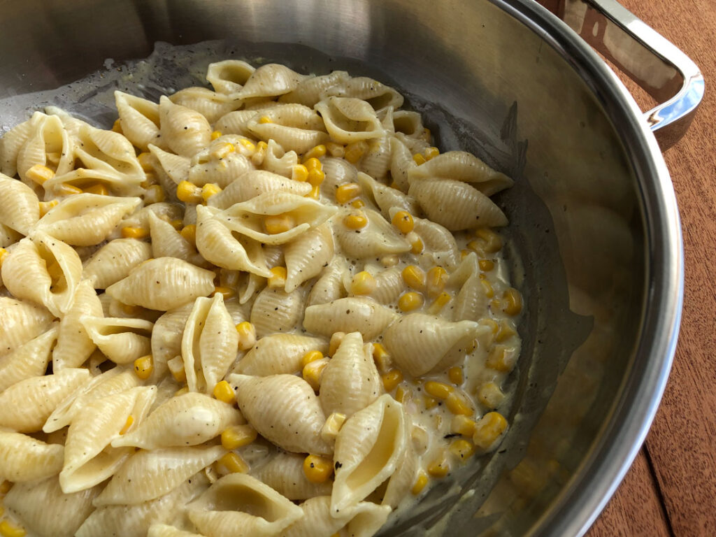 Ready creamy corn pasta in a skillet.