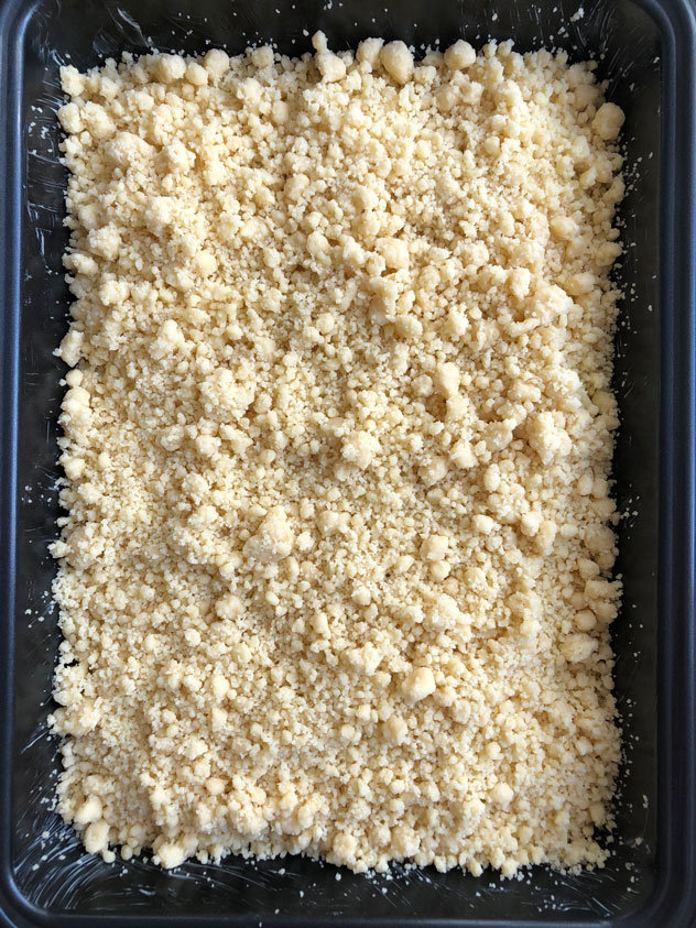 German apple streusel sheet cake, sprinkled with streusel, and ready to bake.