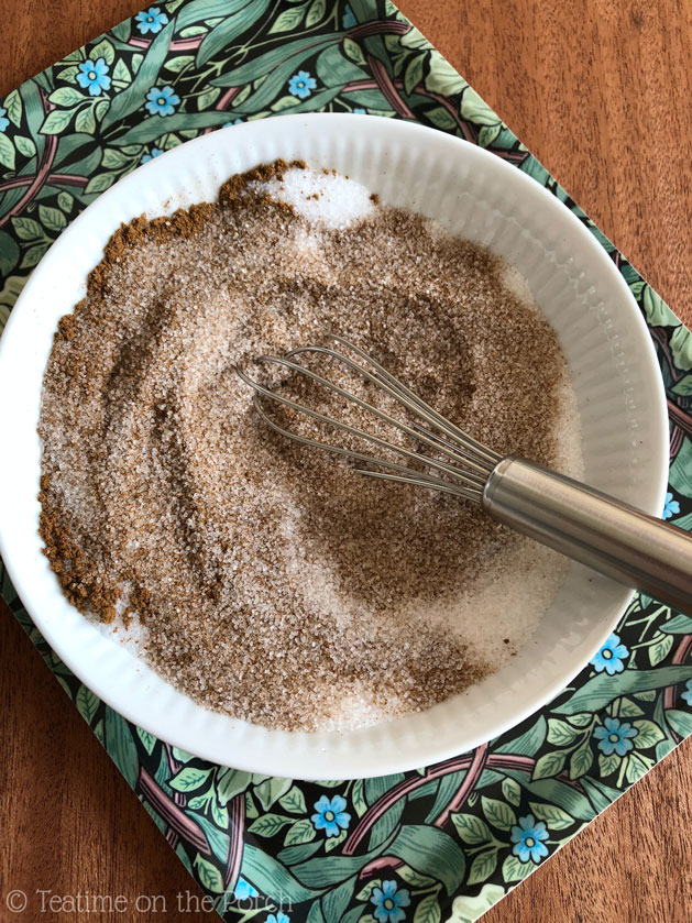Sugar and ground cinnamon in a small bowl with a whisk, during the mixing process.
