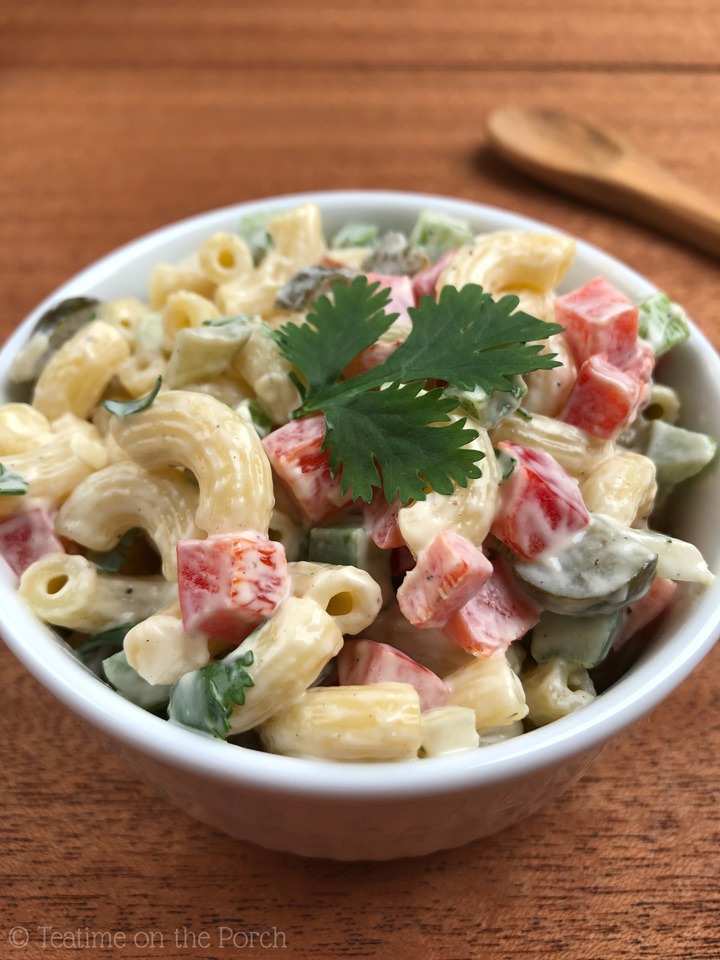 Classic Macaroni Salad Colorful classic macaroni salad in a small bowl, decorated with a flat-leaf parsley leaf.