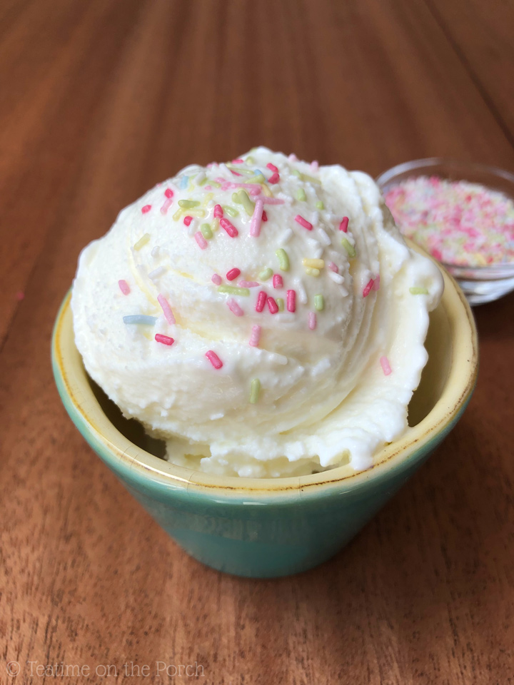 The Best Homemade Frozen Yogurt Creamy homemade frozen yogurt, topped with colorful sugar sprinkles, served in a small turquoise cup, with a small glass bowl filled with colorful sugar sprinkles in the background.