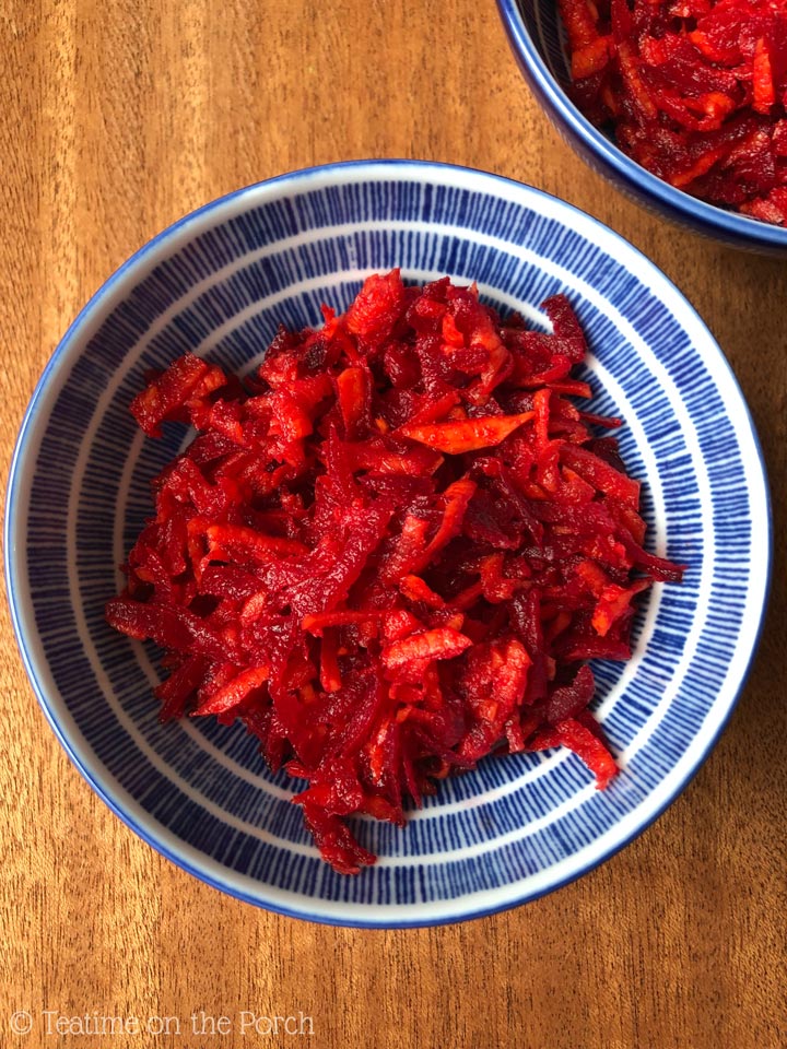 Raw beet carrot salad in a blue and white patterned bowl.
