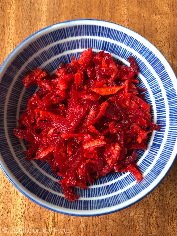 Raw beet carrot salad in a blue and white patterned bowl.