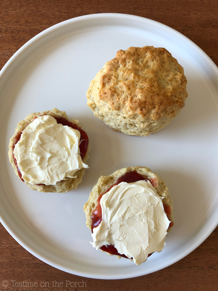 Classic British Scone Recipe Classic British scones on a plate served with strawberry jam and clotted cream, from a bird's-eye view.